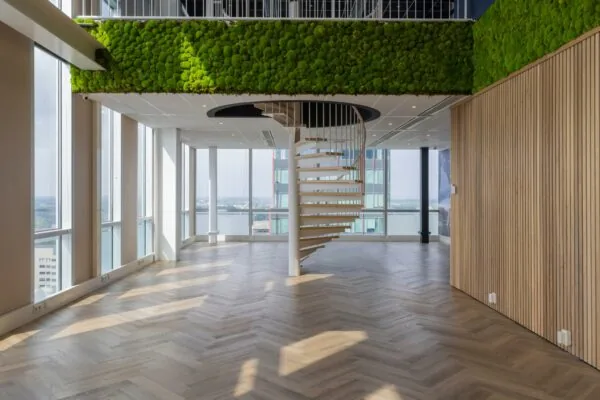 Licht en modern interieur op het Mandelaplein met houten visgraatvloer, groene moswand en spiraaltrap.