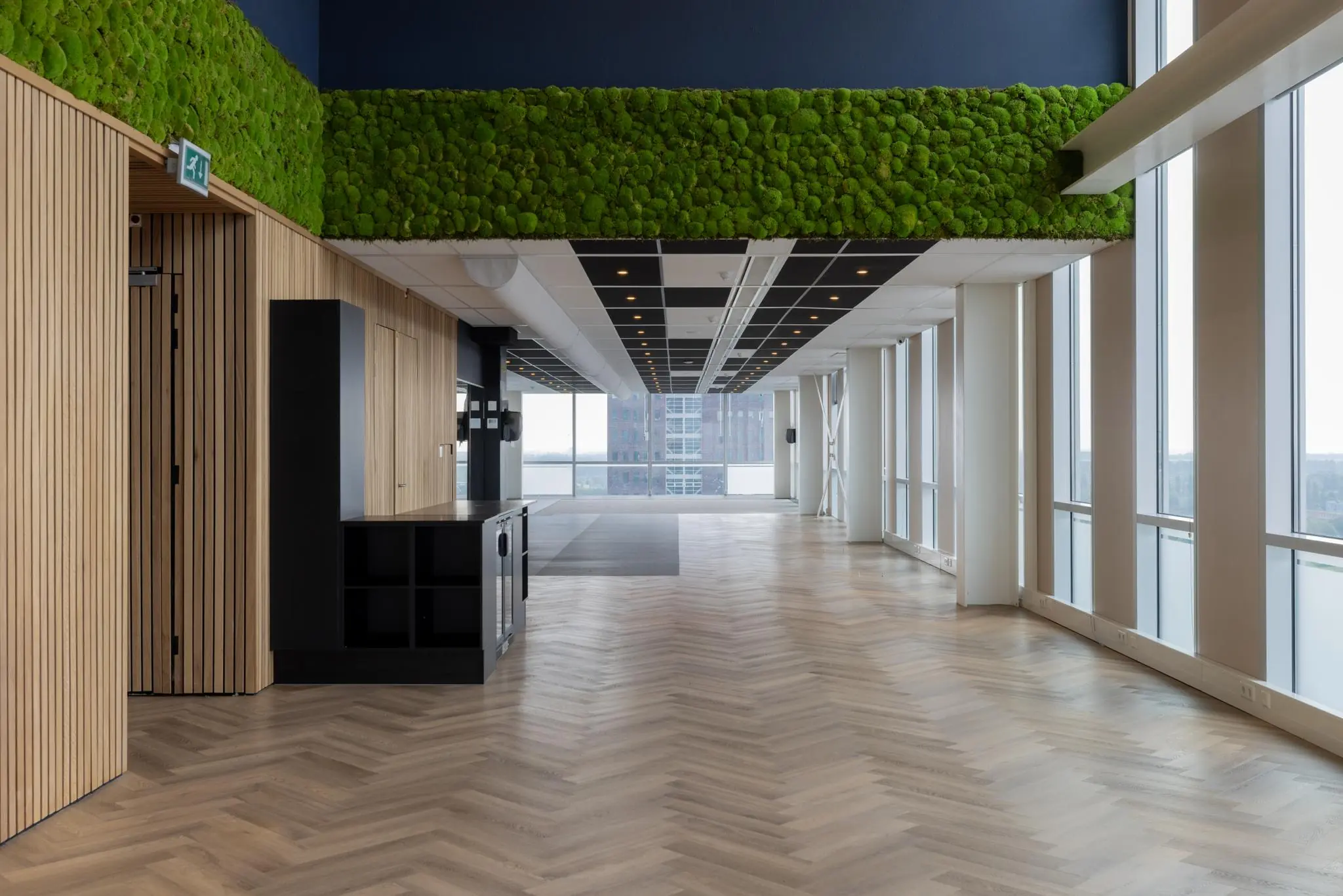 Moderne, lichte kantoorruimte aan het Mandelaplein met houten vloer, moswand en grote ramen met uitzicht op de stad.