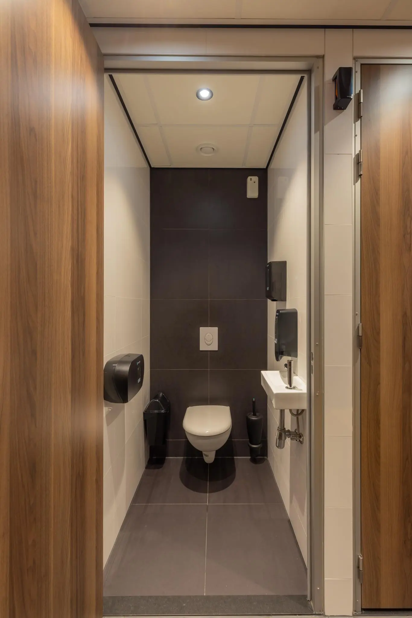 Modern en schoon toilet met hangend closet, fonteintje en houten deur op het Mandelaplein.
