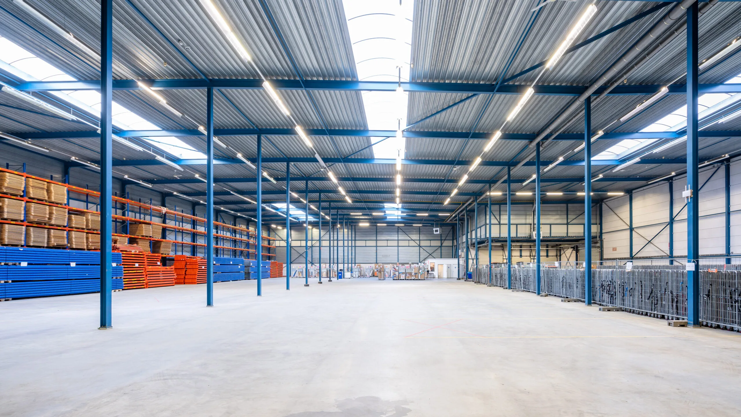 Ruime en goed verlichte magazijnhal met stellingen, opslagrekken en industriële inrichting.
