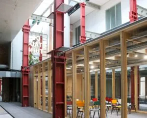 Moderne kantoorruimte met glazen wanden, kleurrijke stoelen en rode stalen balken in verzamelgebouw De Stadstuin aan de Vijf Werelddelen 69 in Rotterdam.