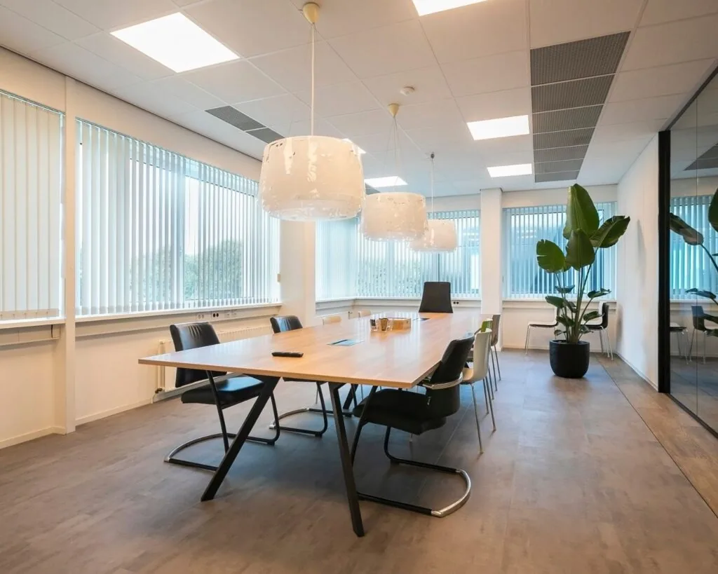 Moderne vergaderruimte in een kantoor aan de Bolderweg 2a in Almere met een lange houten tafel, designstoelen, hanglampen en grote raampartijen met lamellen.