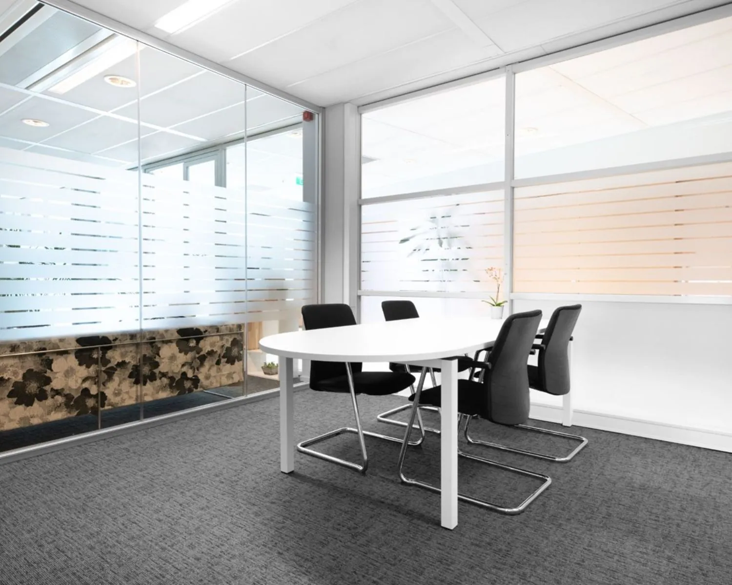 Moderne vergaderruimte met glazen wanden en vier zwarte stoelen in Flight Forum 40, Eindhoven.