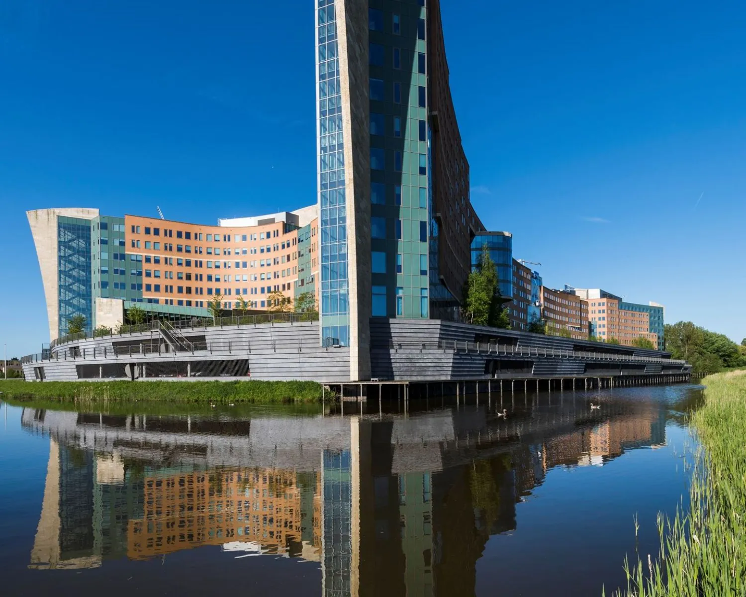 Modern kantoorgebouw aan de Laan van Langerhuizen 1 in Amstelveen, weerspiegeld in het water.