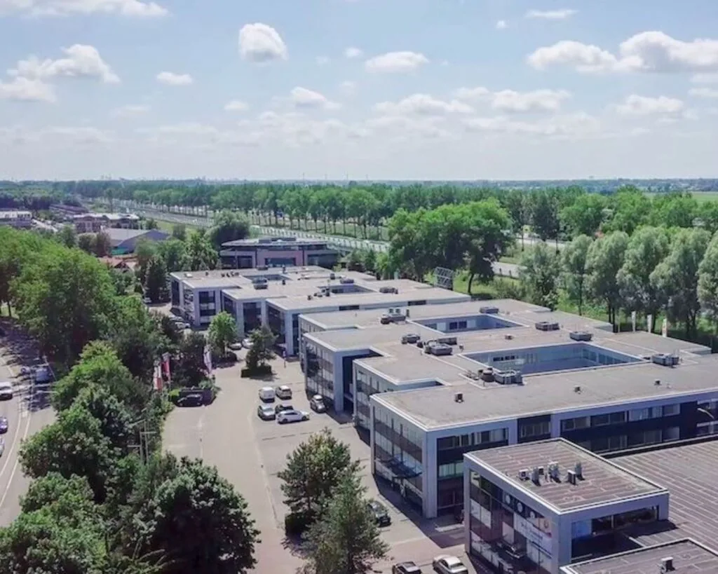 Luchtfoto van moderne kantoorruimtes aan de Reeuwijkse Poort 114 in Reeuwijk, omgeven door groen en wegen.