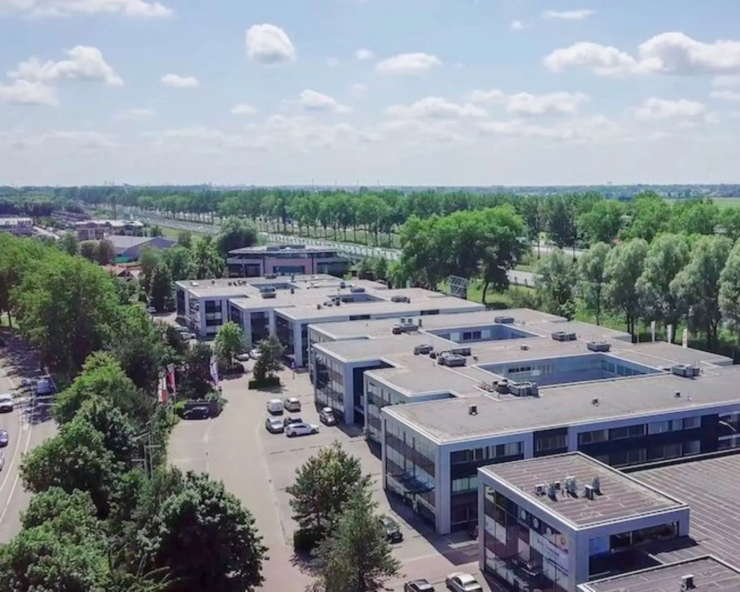 Luchtfoto van moderne kantoorruimtes aan de Reeuwijkse Poort 114 in Reeuwijk, omgeven door groen en wegen.