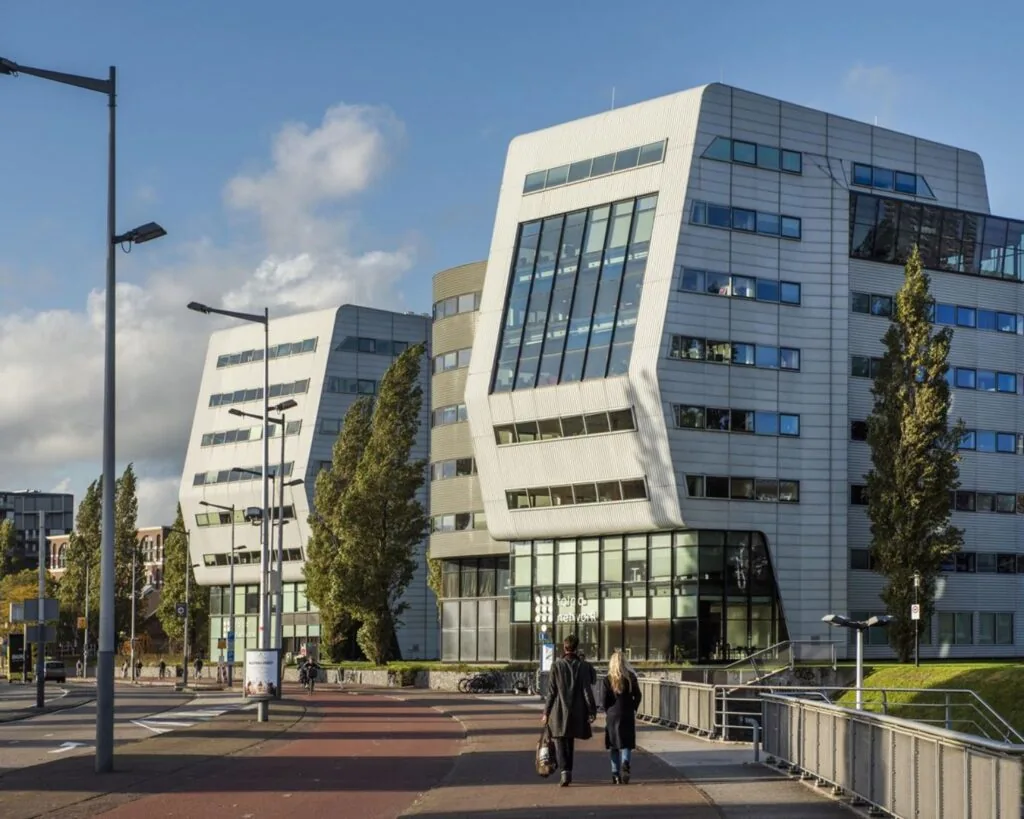 Moderne kantoorgebouwen aan het Rietlandpark in Amsterdam met een opvallende architectuur en een helderblauwe lucht op de achtergrond.