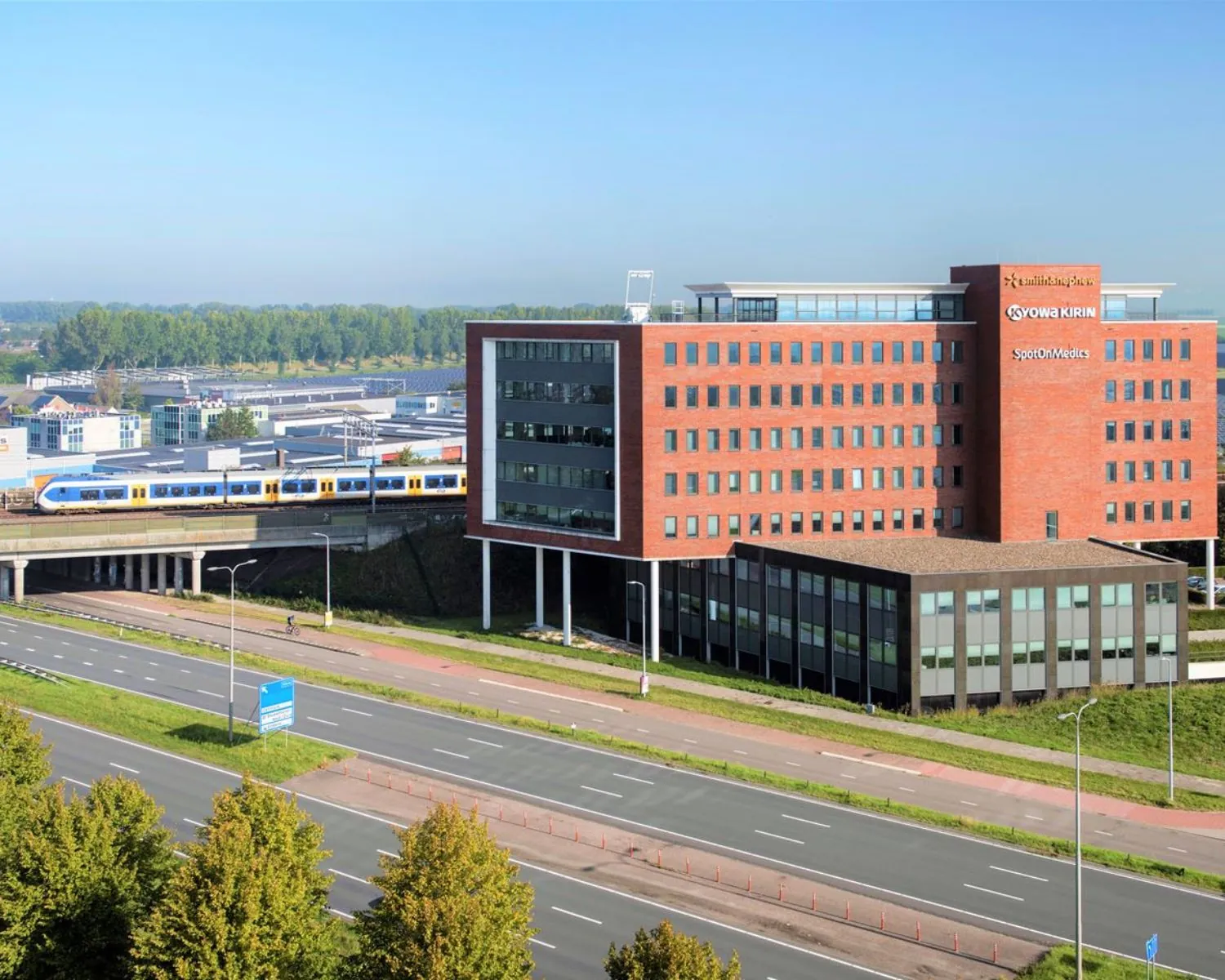 Modern kantoorgebouw aan de Bloemlaan 2 in Hoofddorp, gelegen langs een snelweg en spoorlijn.