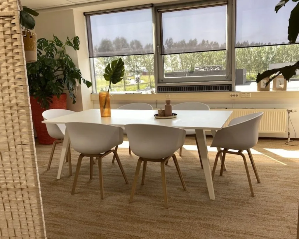 Moderne vergaderruimte met witte tafel, zes designstoelen en grote ramen in een kantoor aan de Kamerlingh Onnesweg 10 in Barendrecht.