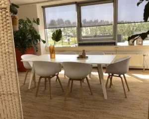 Moderne vergaderruimte met witte tafel, zes designstoelen en grote ramen in een kantoor aan de Kamerlingh Onnesweg 10 in Barendrecht.