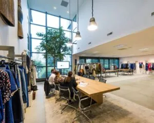 Moderne kantoorruimte in Diemen met hoge ramen, vergadertafel en kledingrekken.