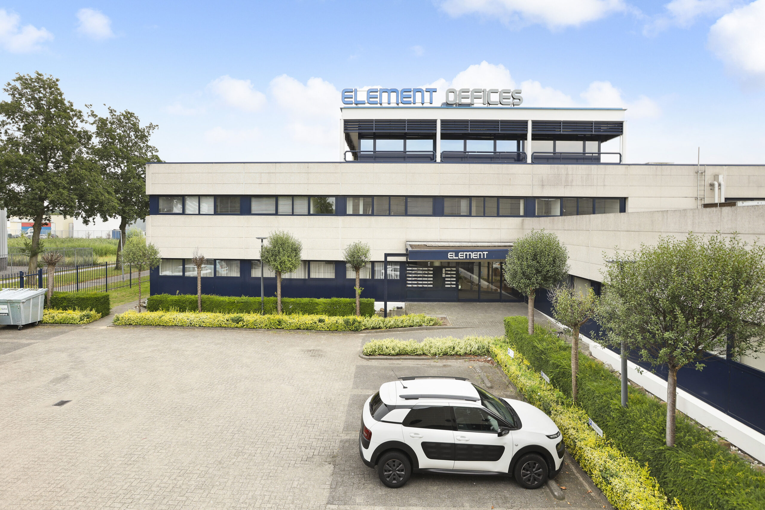 Voorzijde van het Element Offices-gebouw in Almere met parkeerplekken en groene omlijsting.