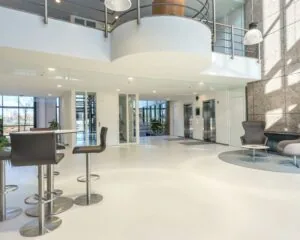 Moderne entree aan de achterkant van een kantoorgebouw met strakke inrichting, zitgedeelte en liften.