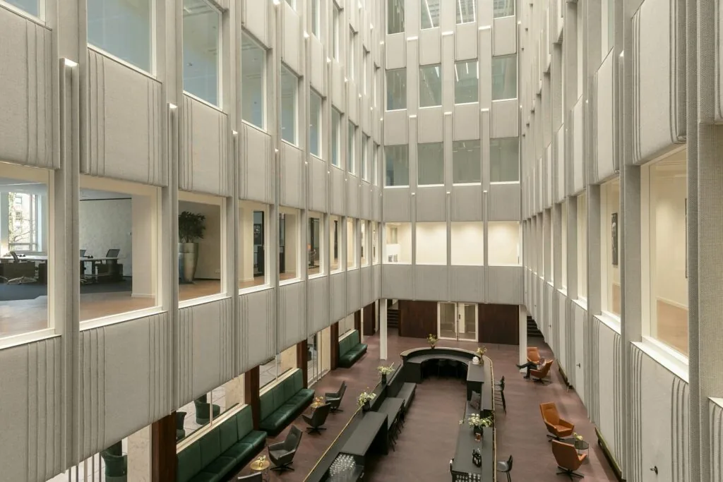 Moderne, open binnenruimte van een kantoorgebouw met zitgedeelte en bureau’s aan de zijkanten van de verdiepingen.