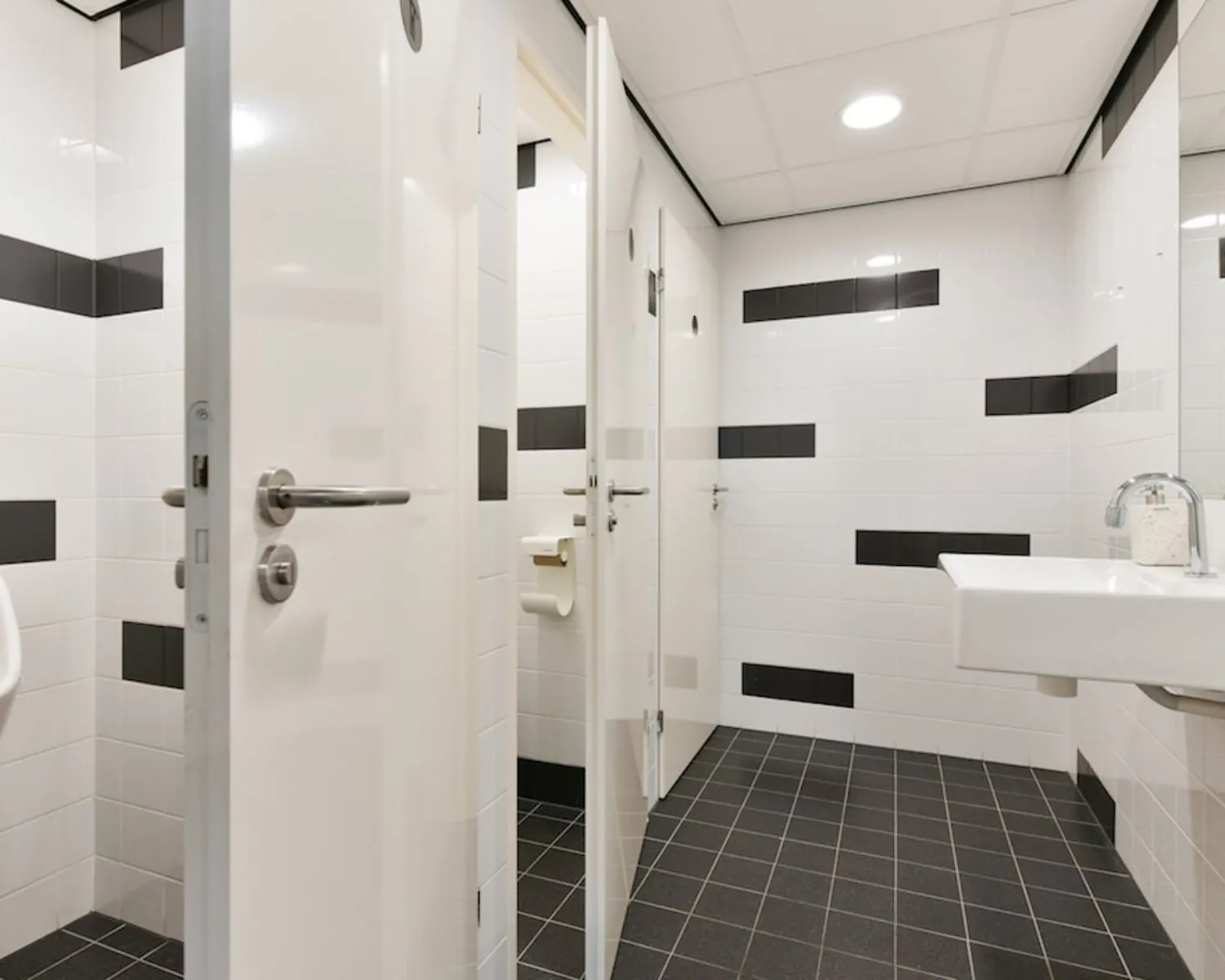 Moderne sanitaire ruimte met witte en zwarte tegels in een kantoorpand aan de Treubstraat 1 in Rijswijk.