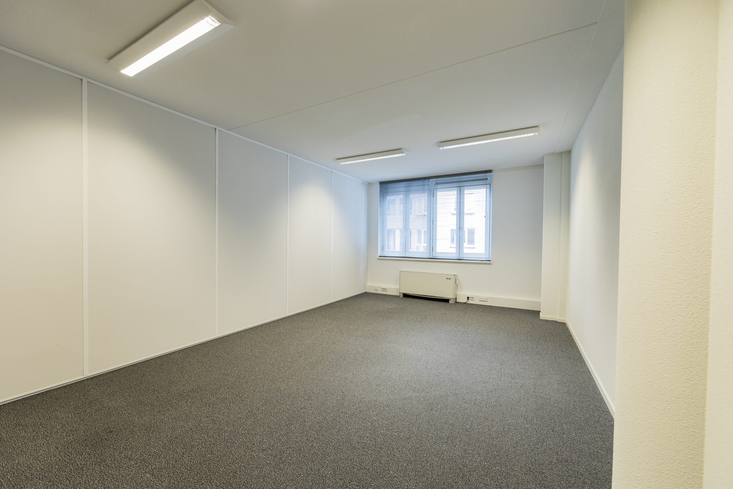 Lege kantoorruimte op de 20e etage van Vleuterweide, met witte muren, grijze vloerbedekking en grote ramen.