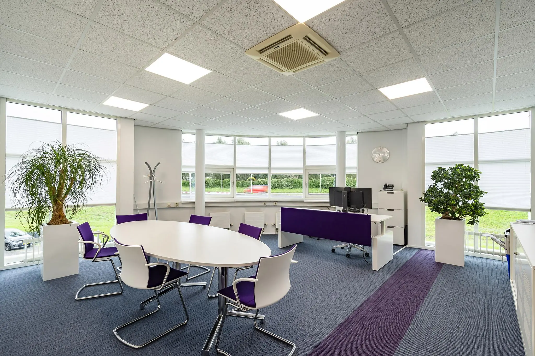 Modern ingericht kantoor op Rhijnspoor met grote ramen, witte meubels en paarse accenten.