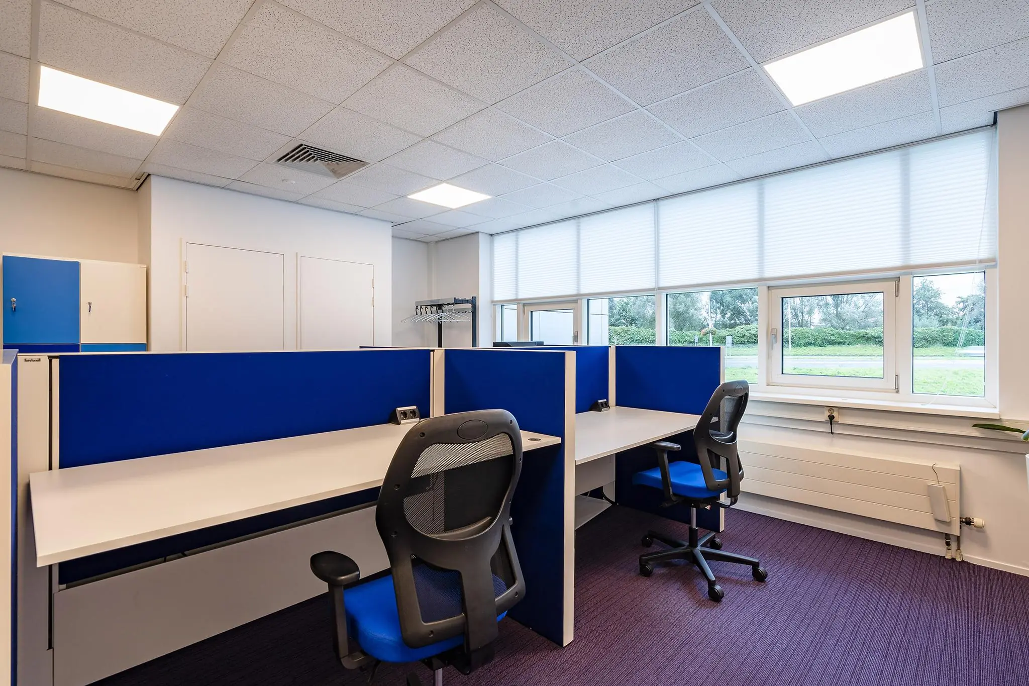 Moderne kantoorruimte aan het Rhijnspoor met werkplekken, bureaustoelen en een groot raam met uitzicht op het groen.