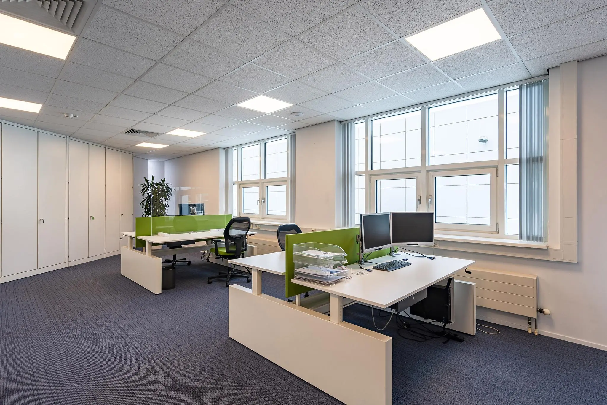 Modern kantoorinterieur aan het Rhijnspoor met werkplekken, computerschermen en grote ramen.