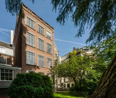 Achteraanzicht van een hoog herenhuis aan de Herengracht met tuin en omliggend groen.
