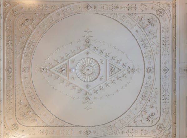 Versierde plafondornamenten in een historisch pand aan de Herengracht met symmetrische florale en geometrische patronen.