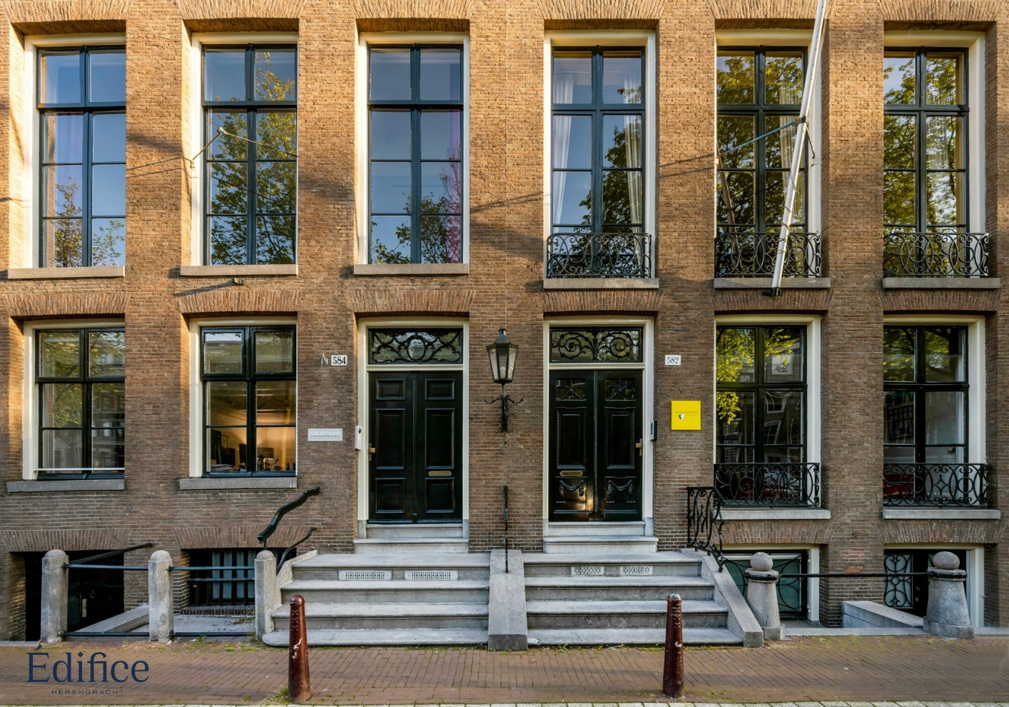 Voorgevel van een klassiek Amsterdams grachtenpand aan de Herengracht met twee entrees en hoge ramen.