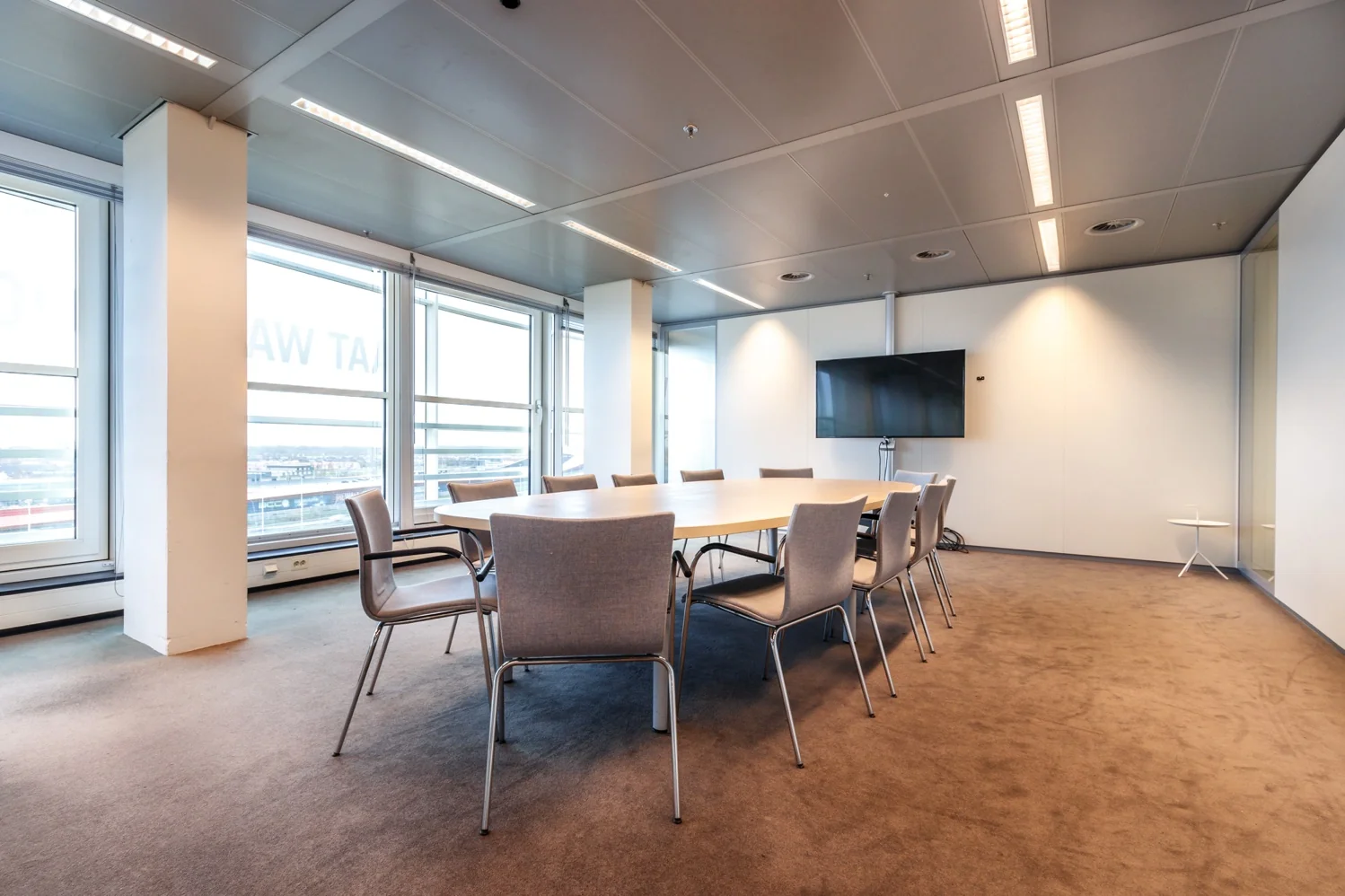 Vergaderruimte aan de Reactorweg met een grote tafel, twaalf stoelen en een flatscreen aan de muur.