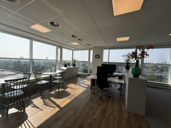 Modern hoekkantoor aan de Newtonlaan met grote ramen, een bureau, zitgedeelte en uitzicht over de stad.