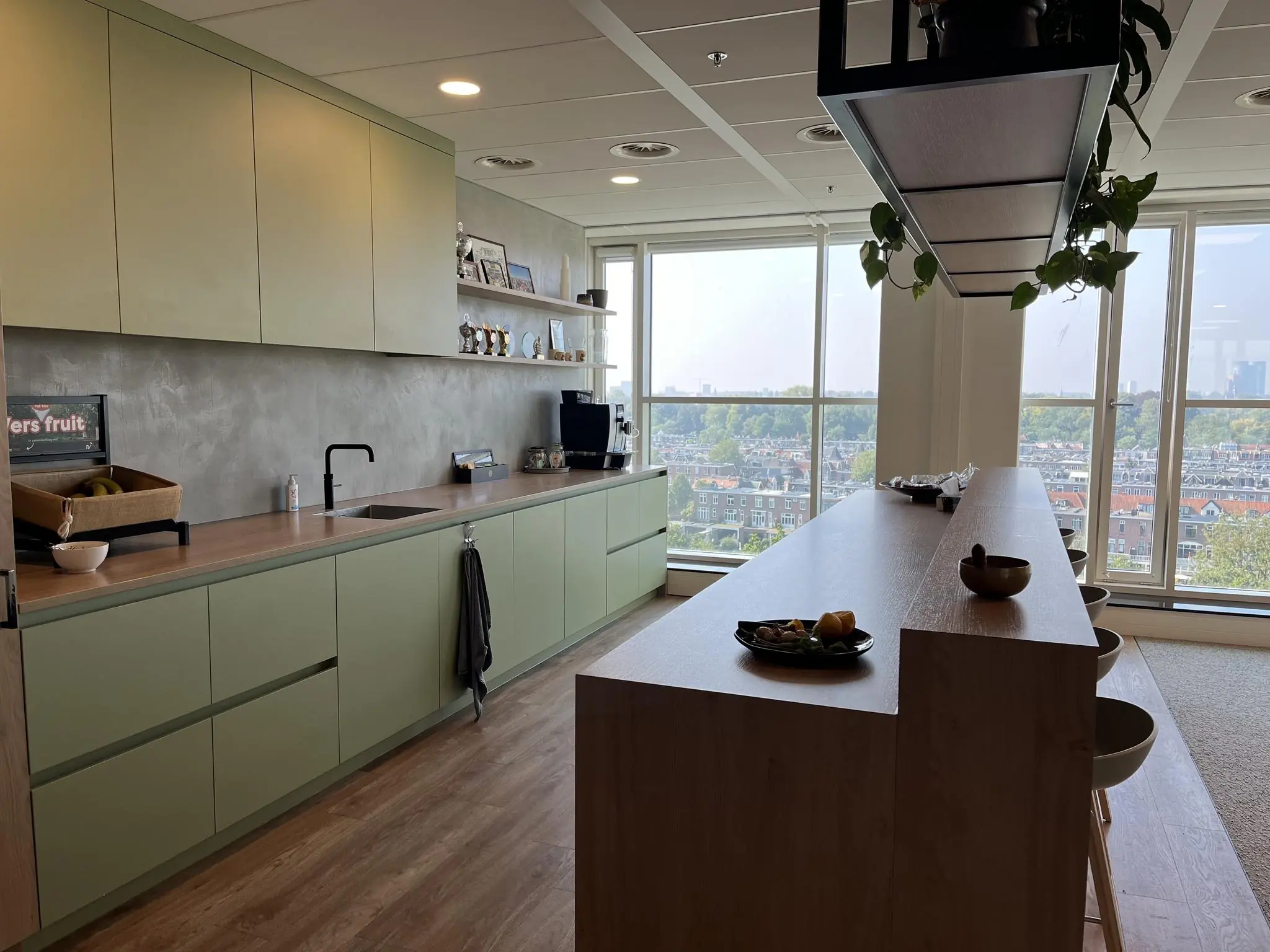Moderne kantoorkeuken aan de Newtonlaan met groen keukendesign, hoge ramen en uitzicht over de stad.