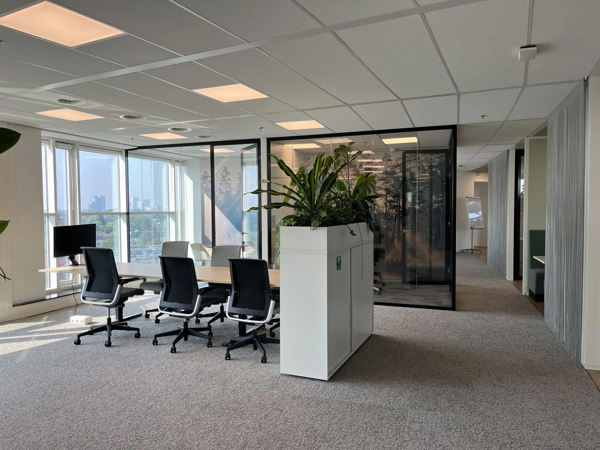 Moderne kantoorruimte aan de Newtonlaan met vergadertafel, bureaustoelen, glazen vergaderruimte en veel daglicht.