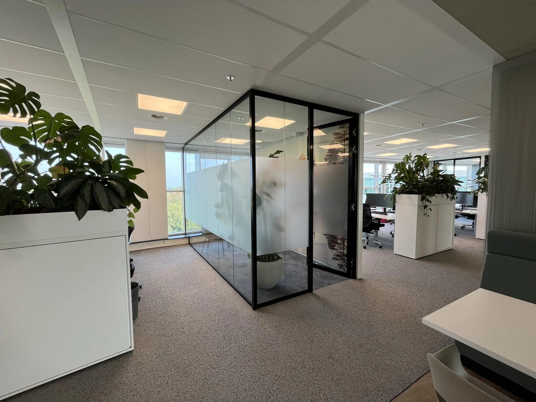 Moderne kantoorruimte aan de Newtonlaan met glazen vergaderruimte en veel groenvoorziening.