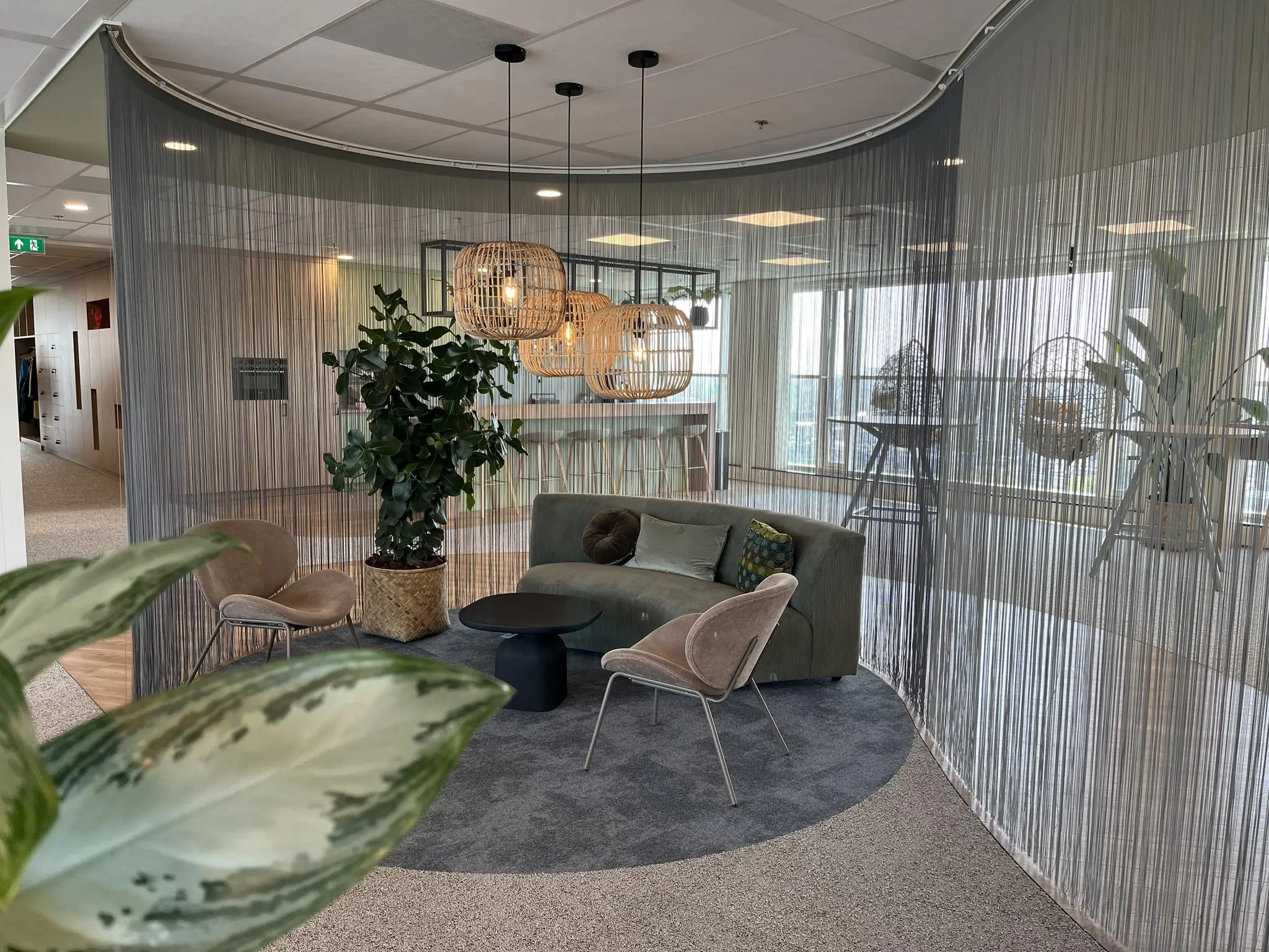 Moderne zithoek op Newtonlaan met stylish meubilair, planten en sfeerverlichting, omgeven door een halfronde draadgordijnwand.
