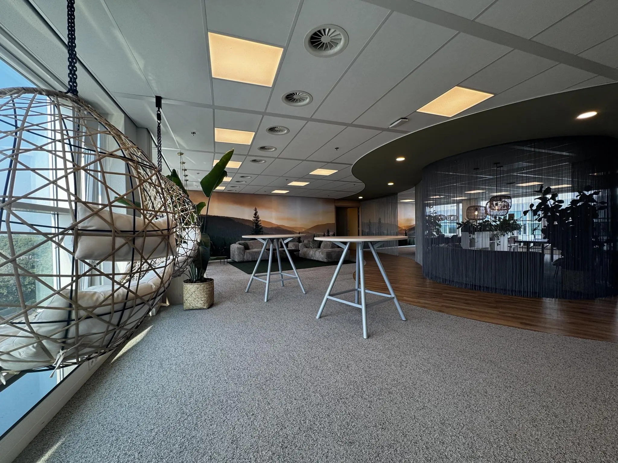 Moderne kantoorruimte aan de Newtonlaan met loungestoelen, hangstoel en planten bij grote ramen.