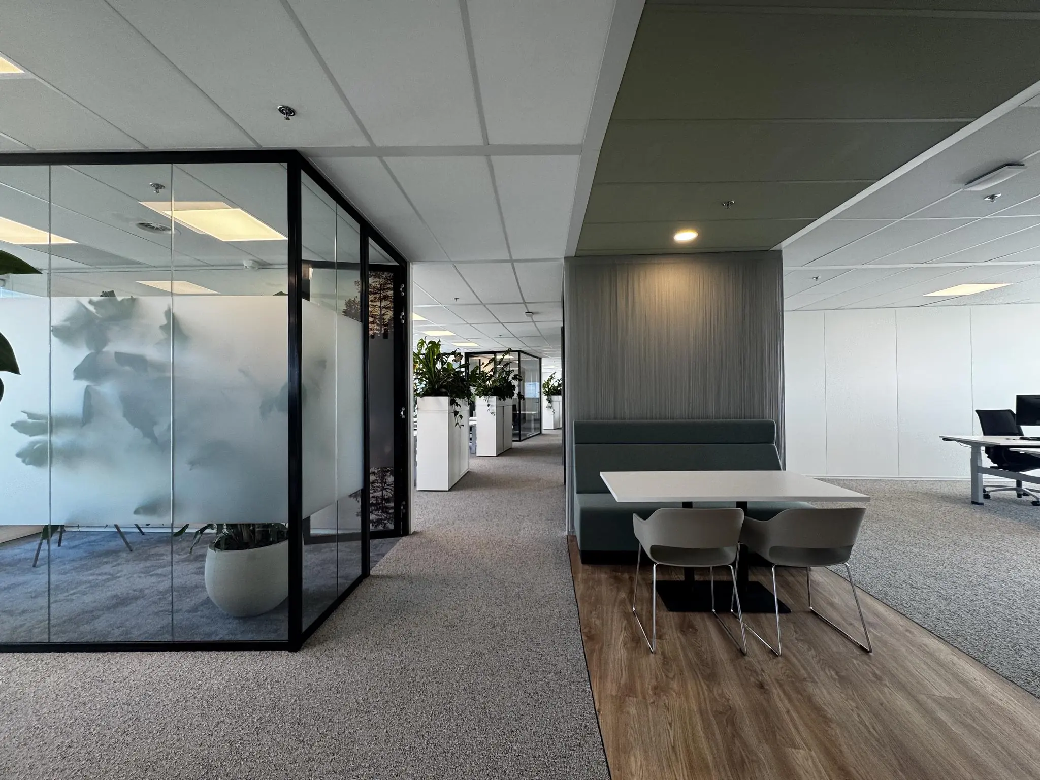 Moderne kantoortuin aan de Newtonlaan met glazen vergaderruimte, planten en een zitplek met tafel.