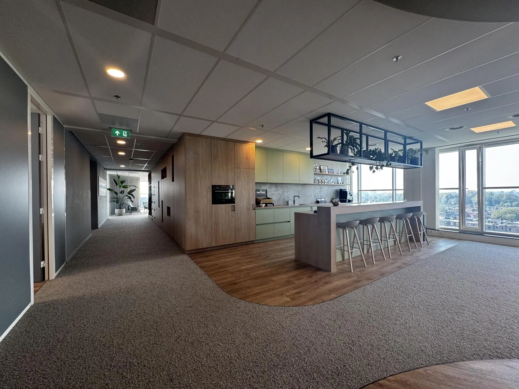 Moderne kantoorkeuken aan de Newtonlaan met bar, zitplaatsen en uitzicht op de stad.