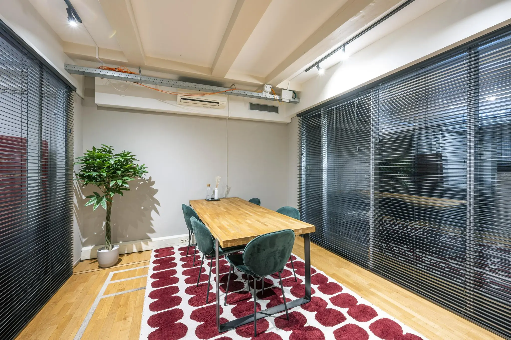Moderne vergaderruimte aan de Herengracht met houten tafel, groene stoelen en rood-wit vloerkleed.