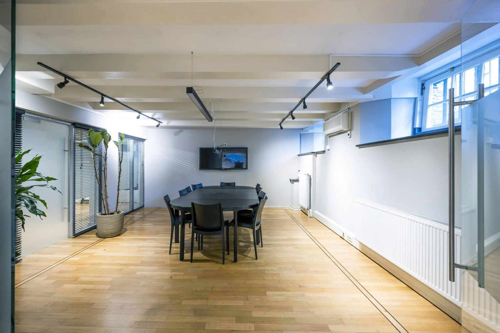 Vergaderruimte aan de Herengracht met een ovale tafel, zwarte stoelen, houten vloer en moderne verlichting.