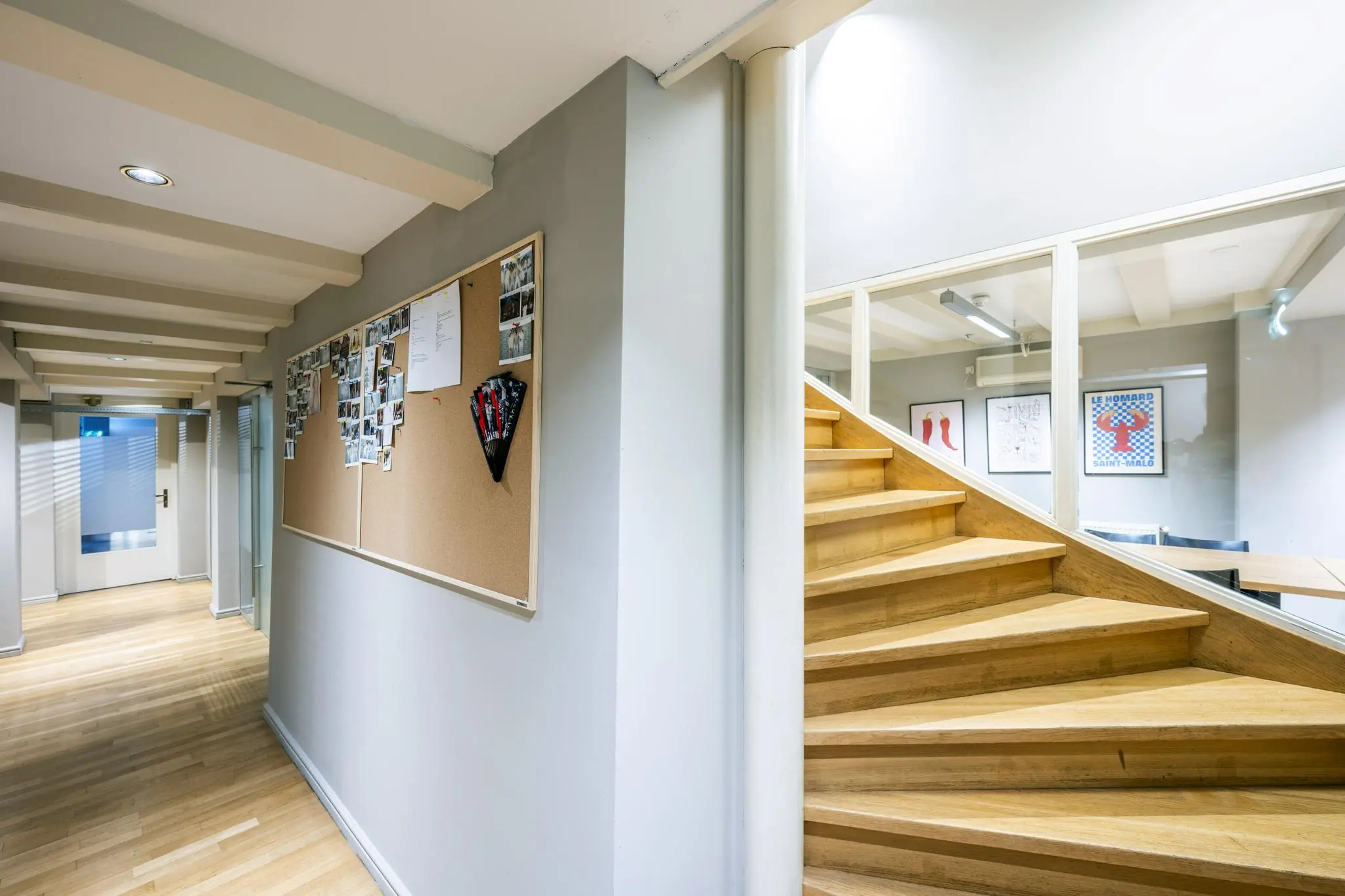 Hal met houten trap, glazen wand en prikbord met foto's in een kantoor aan de Herengracht.