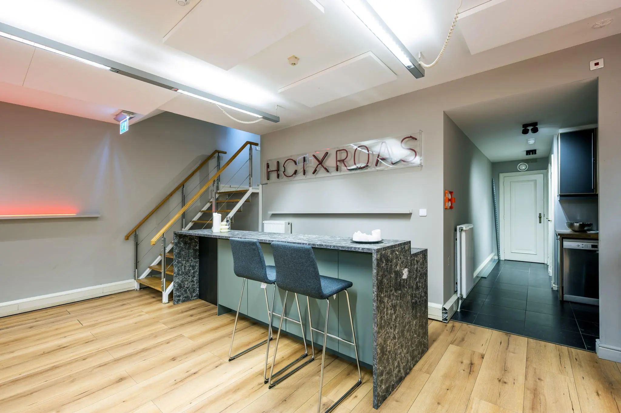 Moderne kantoorruimte aan de Herengracht met een marmeren balie, barkrukken en een trap naar boven.