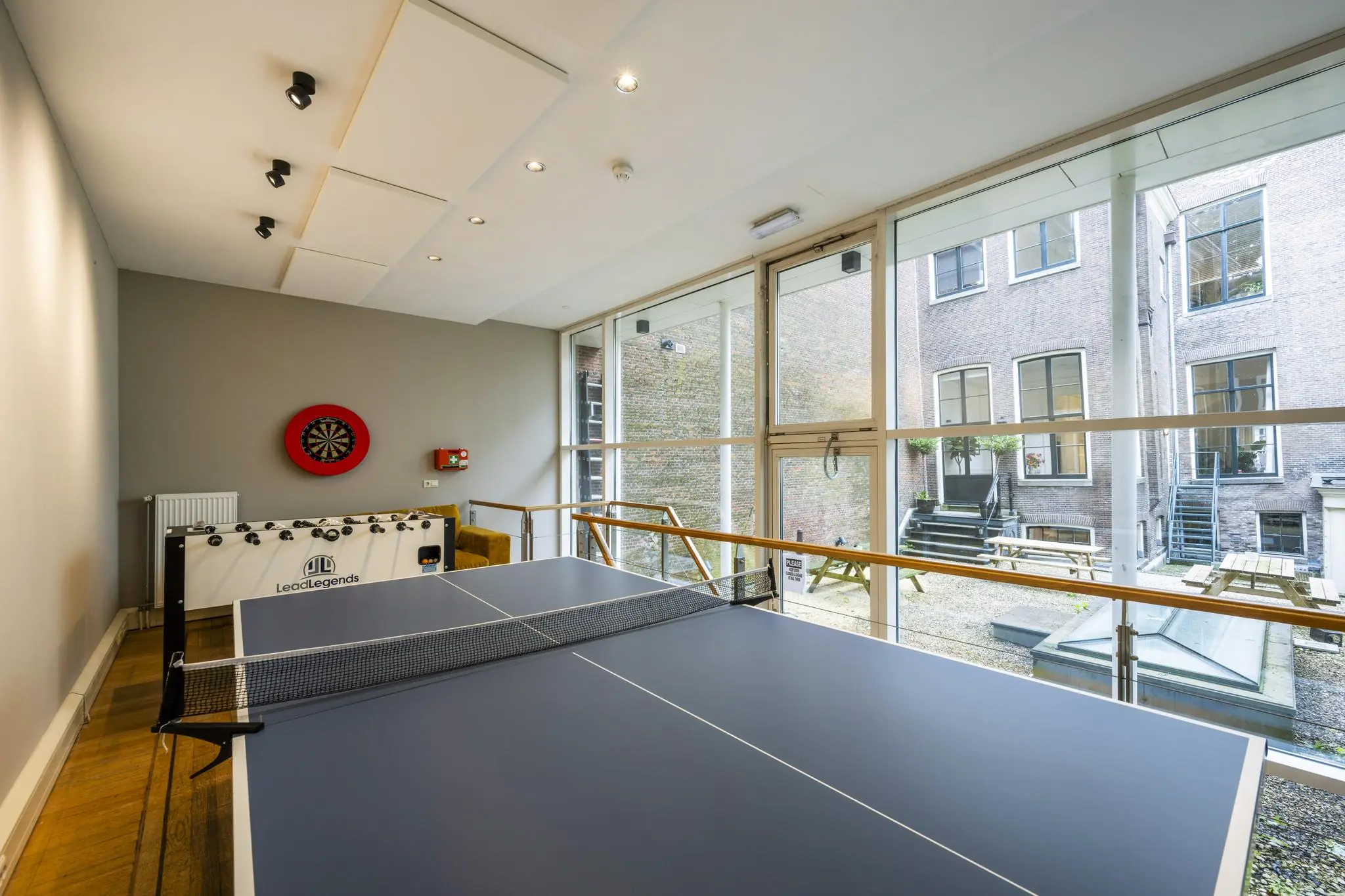 Recreatieruimte aan de Herengracht met een tafeltennistafel, een dartbord en een tafelvoetbaltafel met uitzicht op een binnentuin.