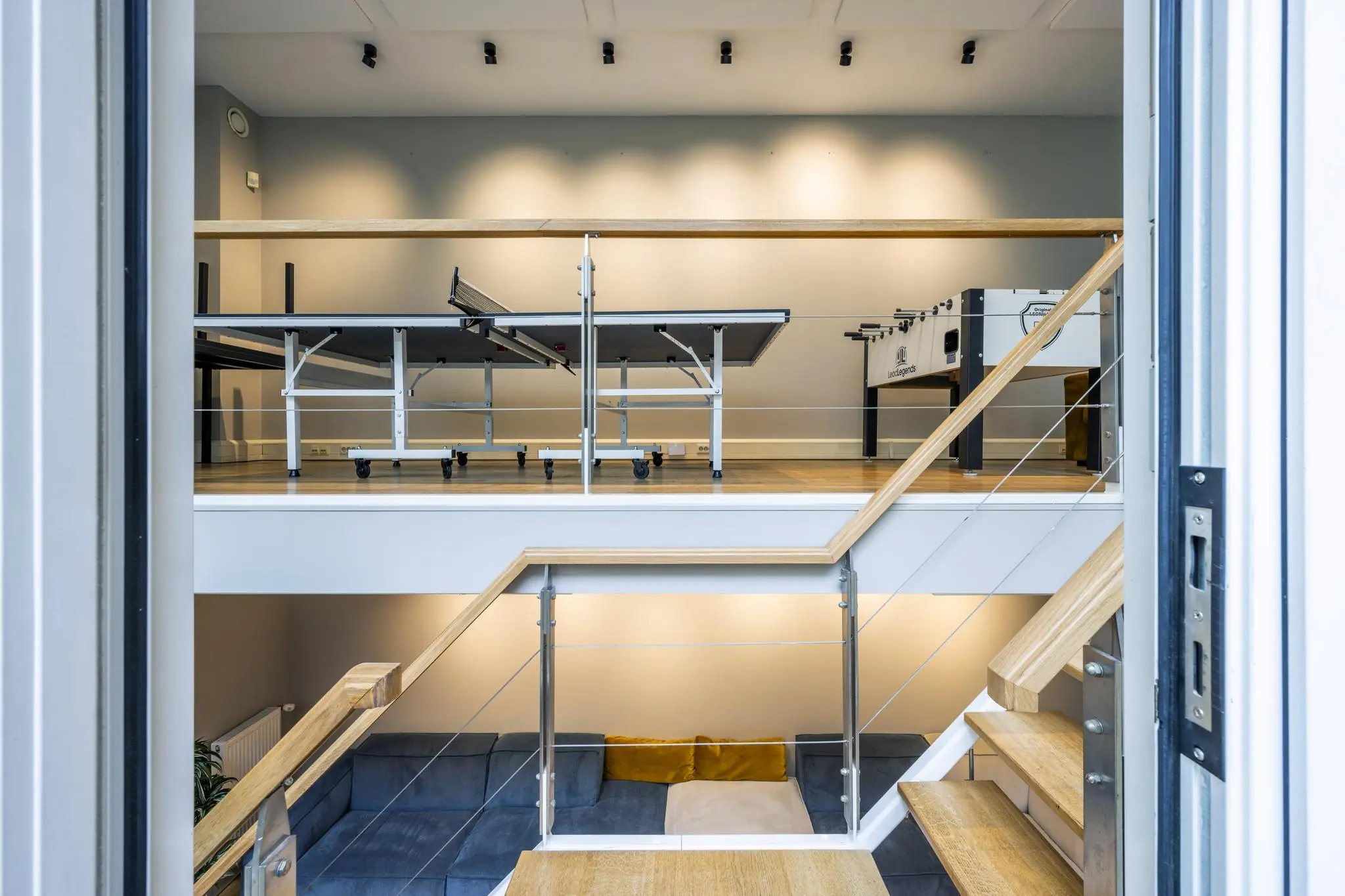 Een moderne split-level ruimte aan de Herengracht met een tafeltennistafel, tafelvoetbaltafel en een zithoek met bank.