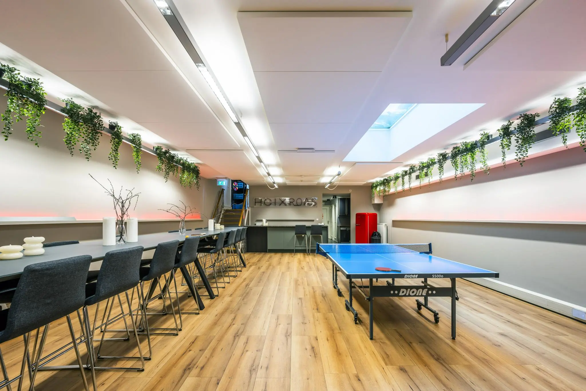 Moderne kantoorruimte aan de Herengracht met een lange vergadertafel, een tafeltennistafel en hangende groene planten.