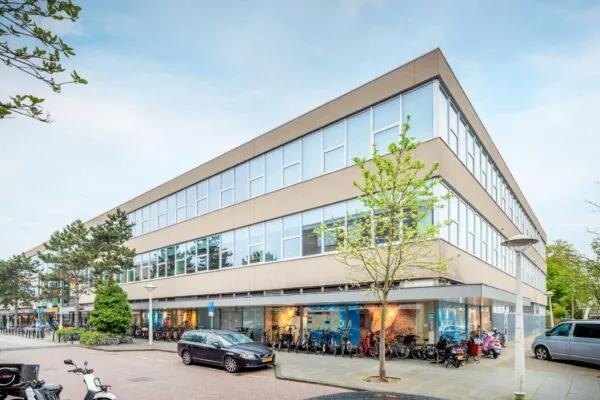 Modern kantoorgebouw aan de Helmholtzstraat met grote ramen, fietsenrekken en geparkeerde voertuigen voor de ingang.