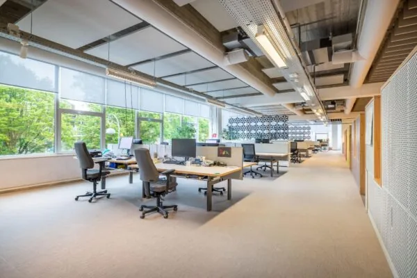 Modern, licht en ruim kantoorinterieur aan de Helmholtzstraat met open werkplekken en grote ramen met uitzicht op groen.