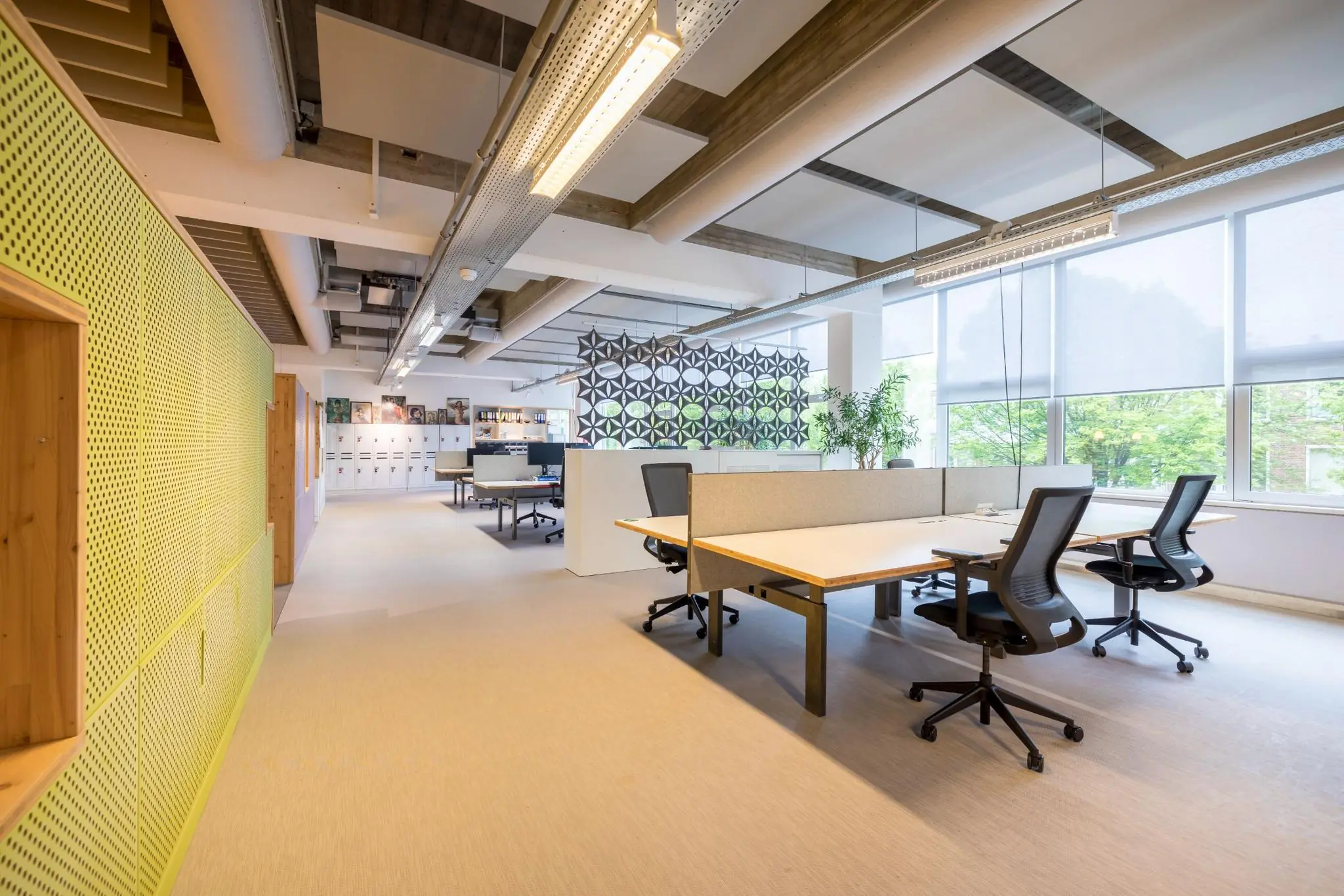Modern en licht open kantoorinterieur aan de Helmholtzstraat met werkplekken, bureaustoelen en grote ramen.