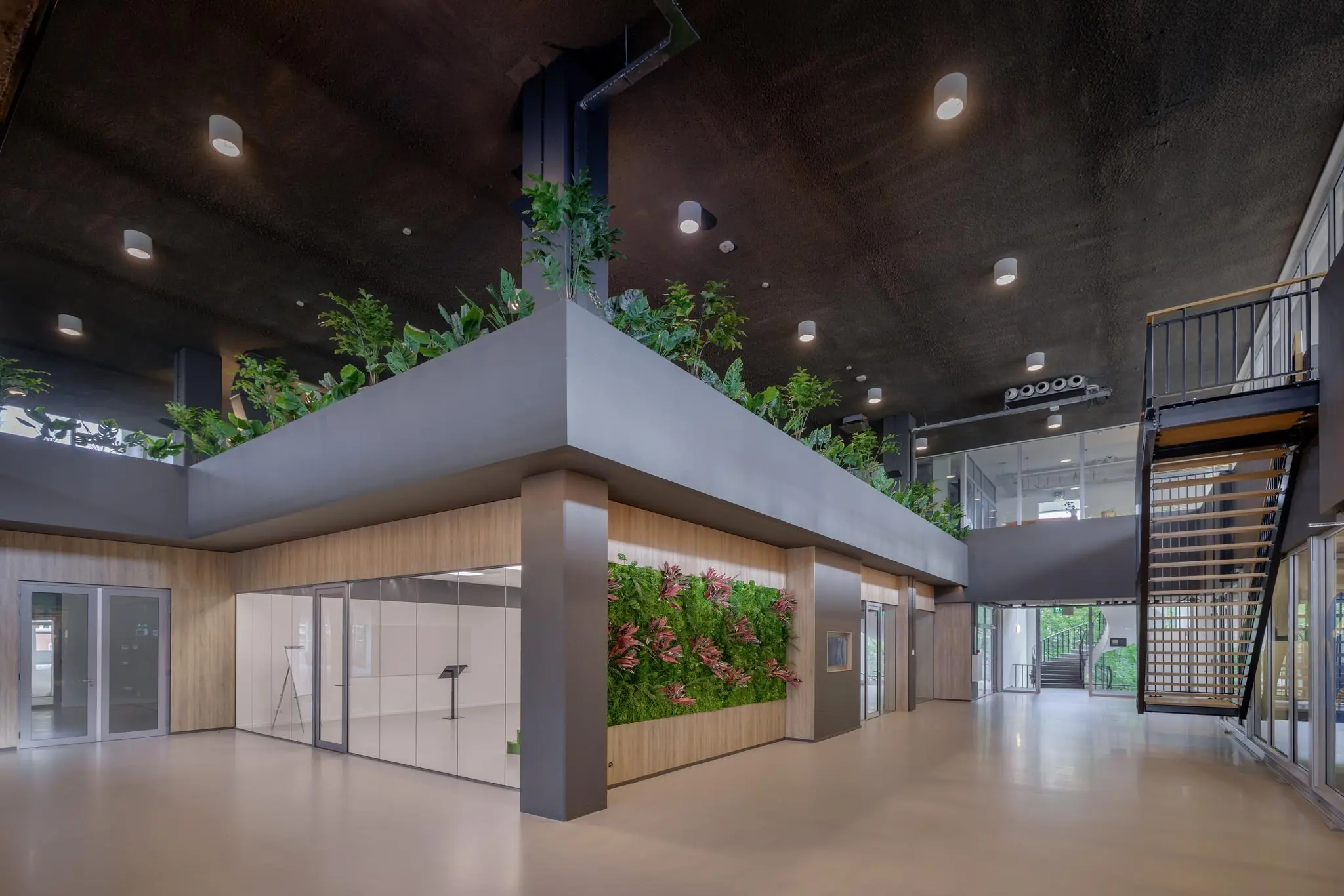 Moderne en lichte entreehal aan de Helmholtzstraat met veel groen, glazen wanden en een industriële trap.