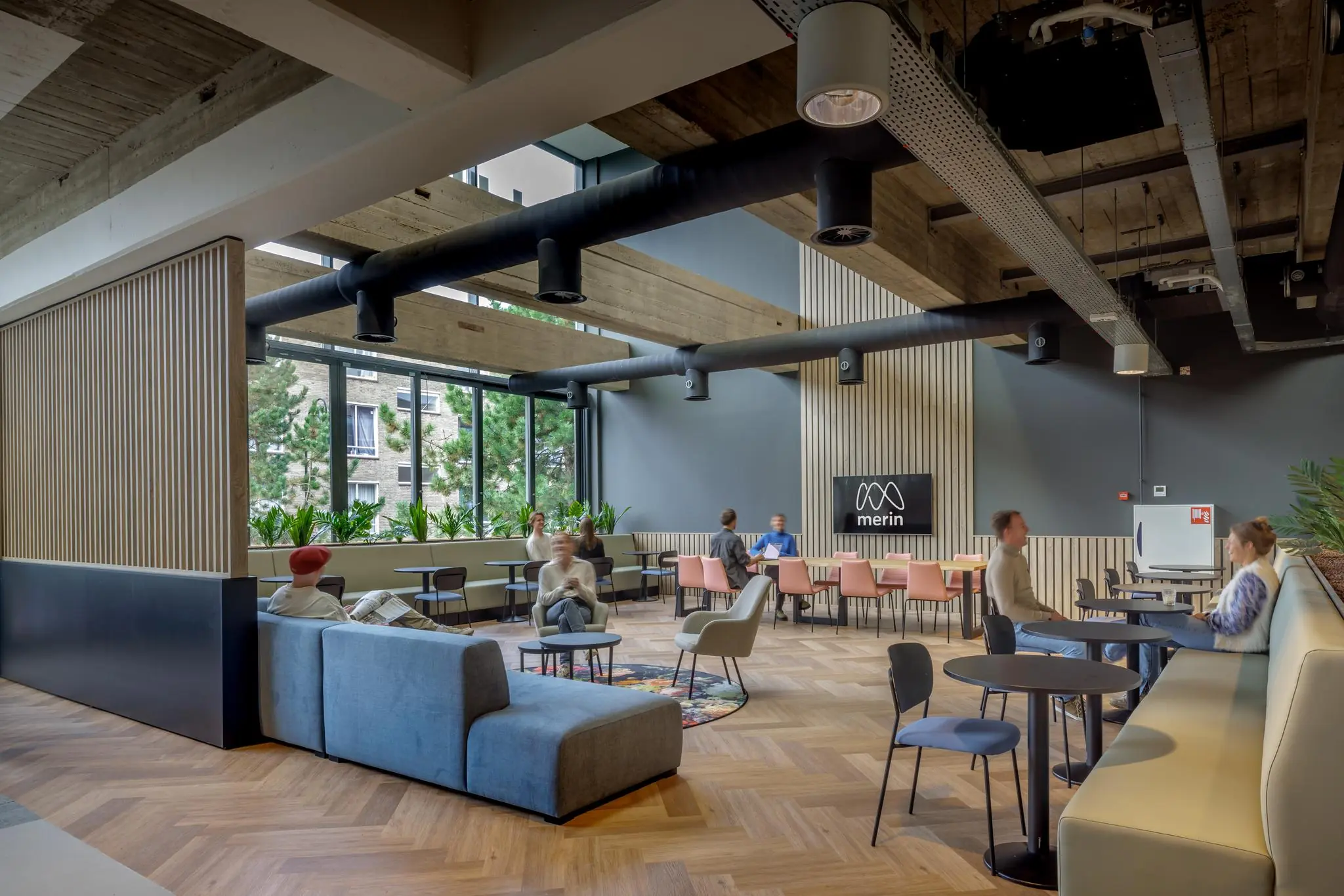 Moderne en lichte kantoorlounge aan de Helmholtzstraat met zithoeken, werkplekken en mensen in gesprek.