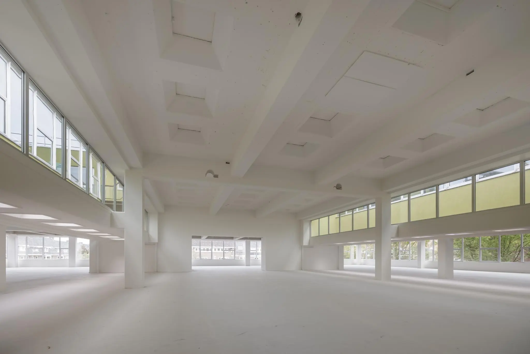 Lichte, lege binnenruimte met hoge plafonds en grote ramen aan de Helmholtzstraat.