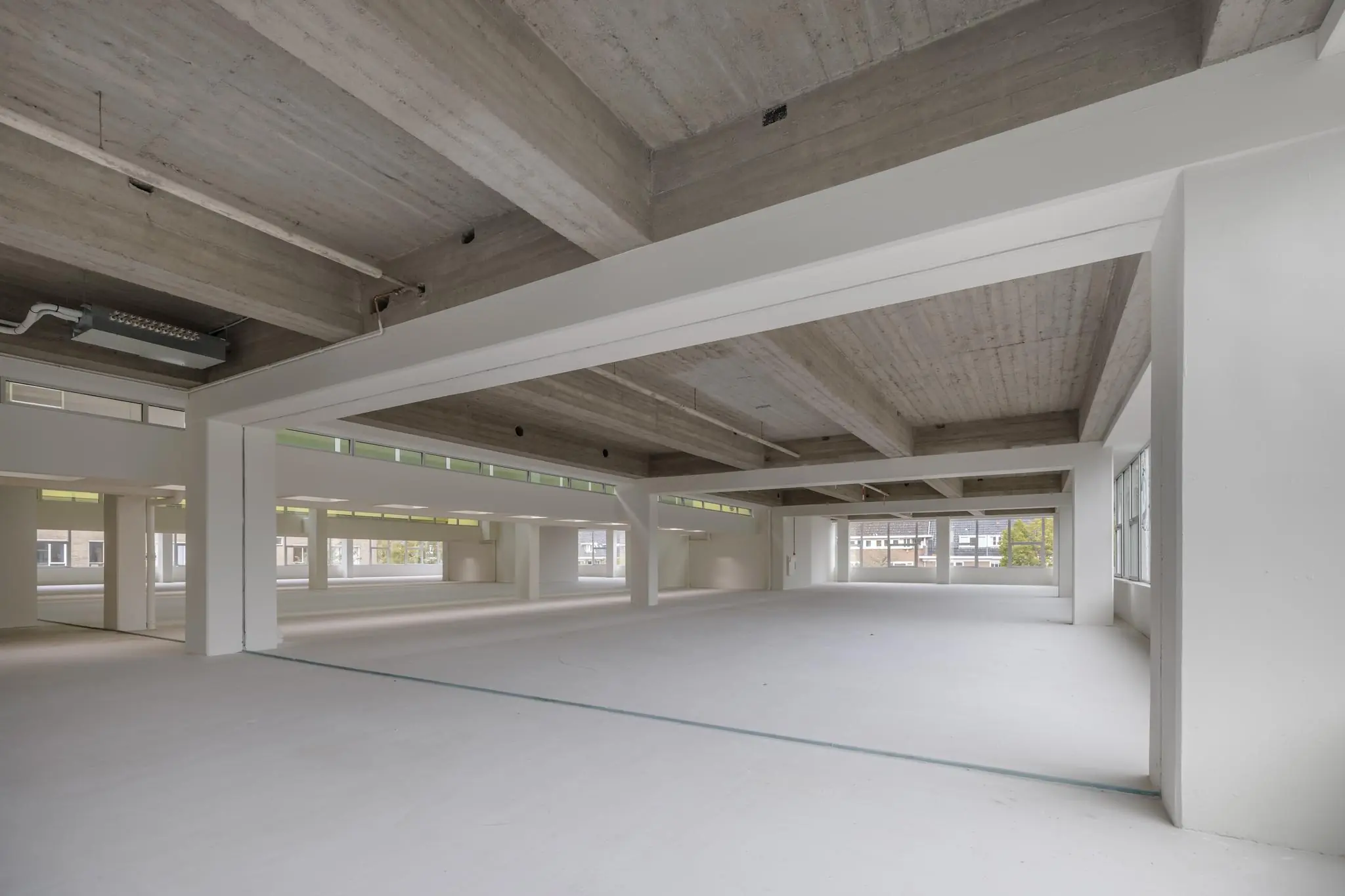 Ruime, lege kantoorruimte met betonnen plafond en grote ramen aan de Helmholtzstraat.