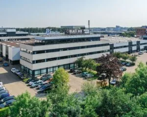 Kantoorgebouw met de bedrijfsnamen Stellar Data Recovery en Black Box Network Services, omgeven door geparkeerde auto's en groen.